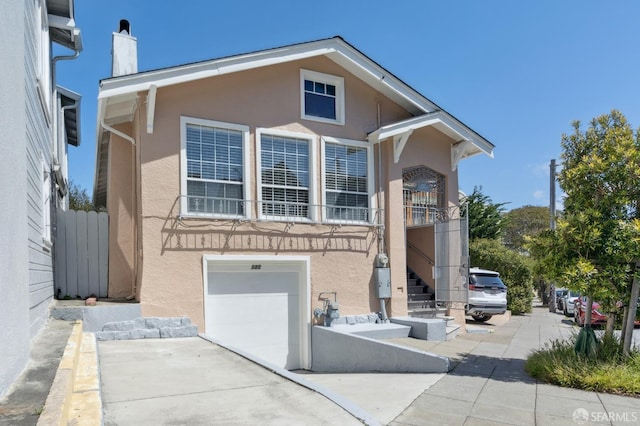 traditional home featuring a garage, stucco siding, and a chimney