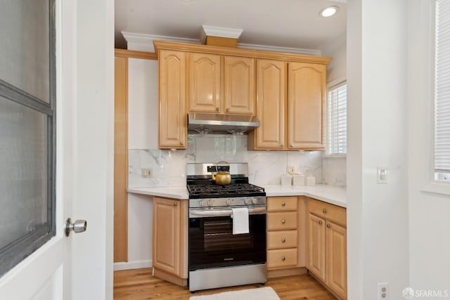 kitchen with ornamental molding, decorative backsplash, light brown cabinets, stainless steel gas range, and under cabinet range hood