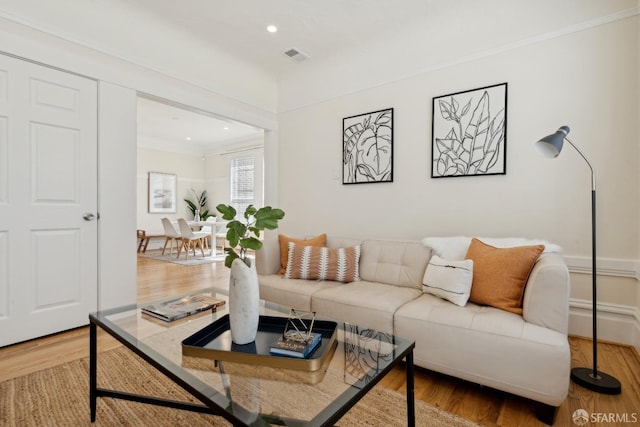 living room featuring visible vents, ornamental molding, wood finished floors, and recessed lighting