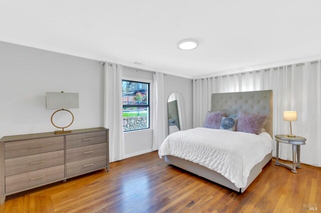 bedroom featuring wood finished floors, ornamental molding, and baseboards