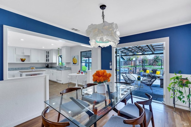 dining space with a chandelier, ornamental molding, light wood finished floors, and recessed lighting