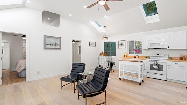 interior space with ceiling fan, white appliances, white cabinetry, a skylight, and light wood finished floors