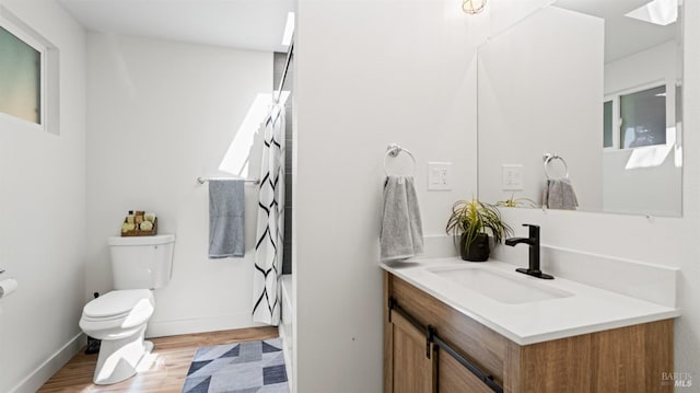 bathroom featuring baseboards, toilet, shower / bath combo with shower curtain, vanity, and wood finished floors