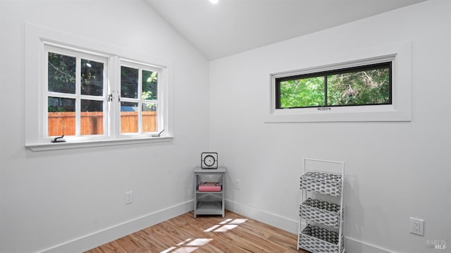 interior space featuring light wood-type flooring, baseboards, vaulted ceiling, and a wealth of natural light