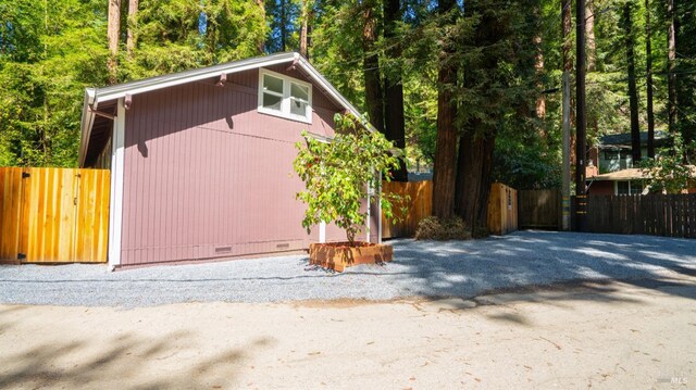 view of side of property with crawl space, an outbuilding, fence, and a gate