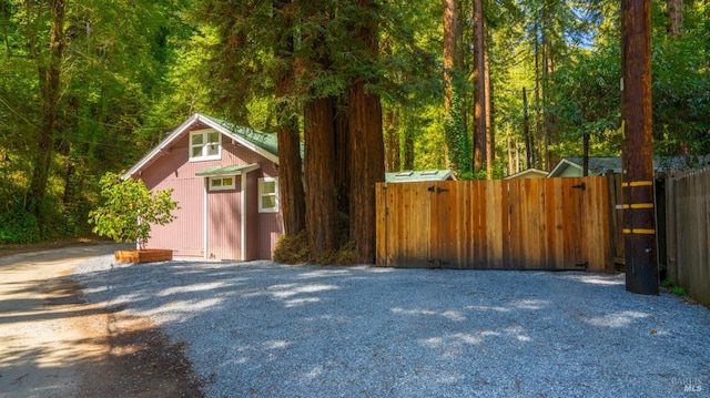 exterior space featuring a view of trees, fence, and an outbuilding