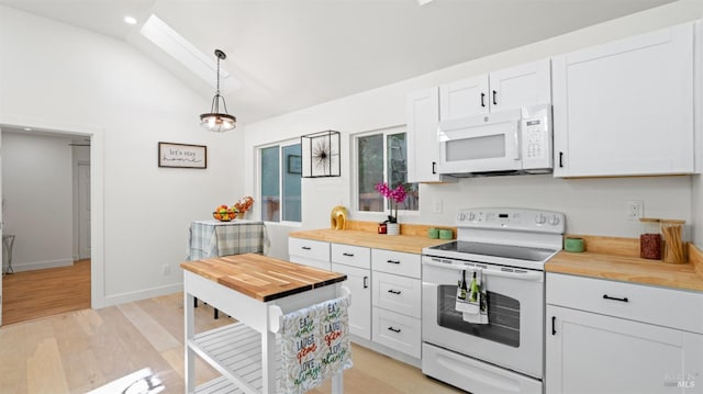 kitchen featuring butcher block countertops, white cabinets, vaulted ceiling with skylight, and white appliances