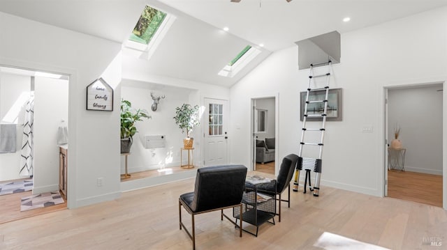 dining space featuring baseboards, light wood-type flooring, recessed lighting, a skylight, and high vaulted ceiling