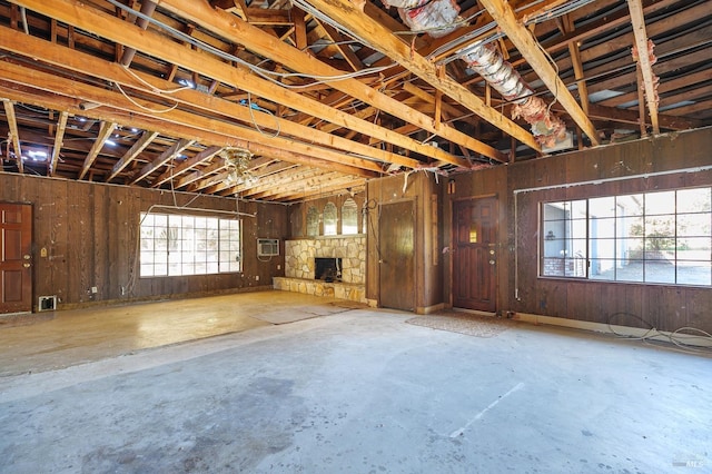 unfurnished living room with concrete flooring, a wall mounted AC, and a fireplace
