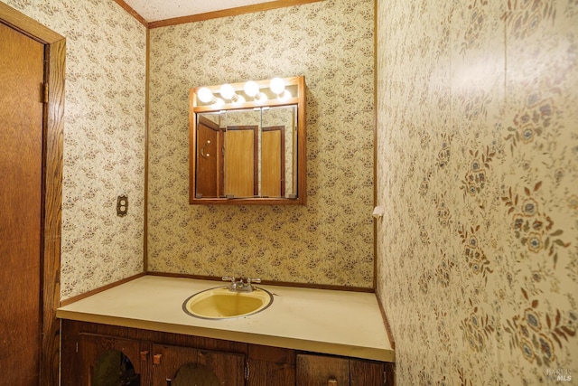 bathroom featuring ornamental molding, vanity, and wallpapered walls