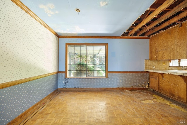 interior space with baseboards, light countertops, brown cabinets, and wallpapered walls