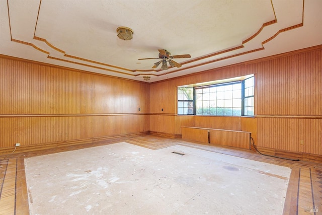unfurnished room with a tray ceiling, a ceiling fan, and crown molding