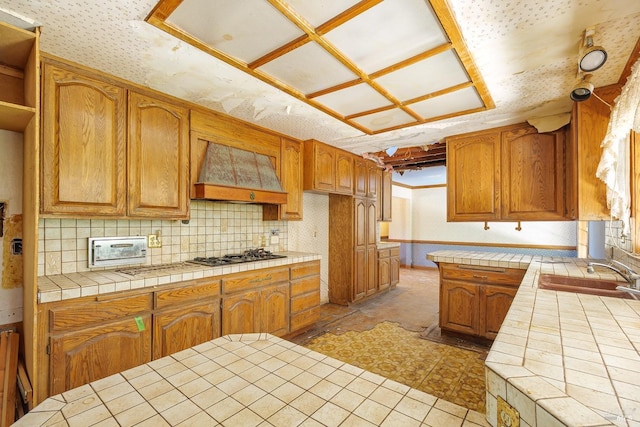 kitchen featuring wallpapered walls, premium range hood, a sink, and tile counters