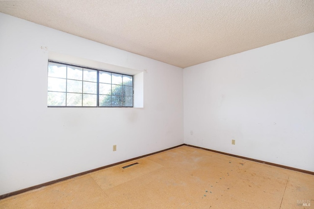 empty room featuring visible vents, baseboards, and a textured ceiling