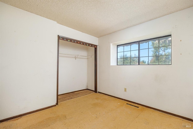unfurnished bedroom with a textured ceiling, a closet, and baseboards