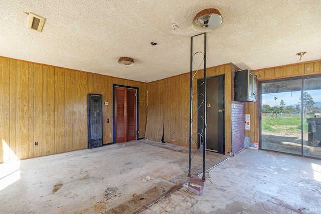 interior space featuring wooden walls and a textured ceiling