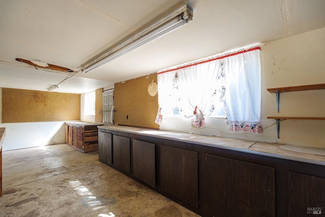 kitchen featuring light countertops, unfinished concrete flooring, and dark brown cabinets