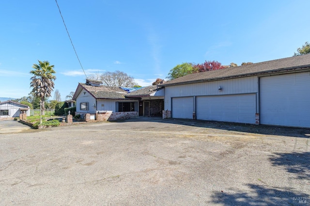 view of front of home with aphalt driveway, stone siding, and an attached garage