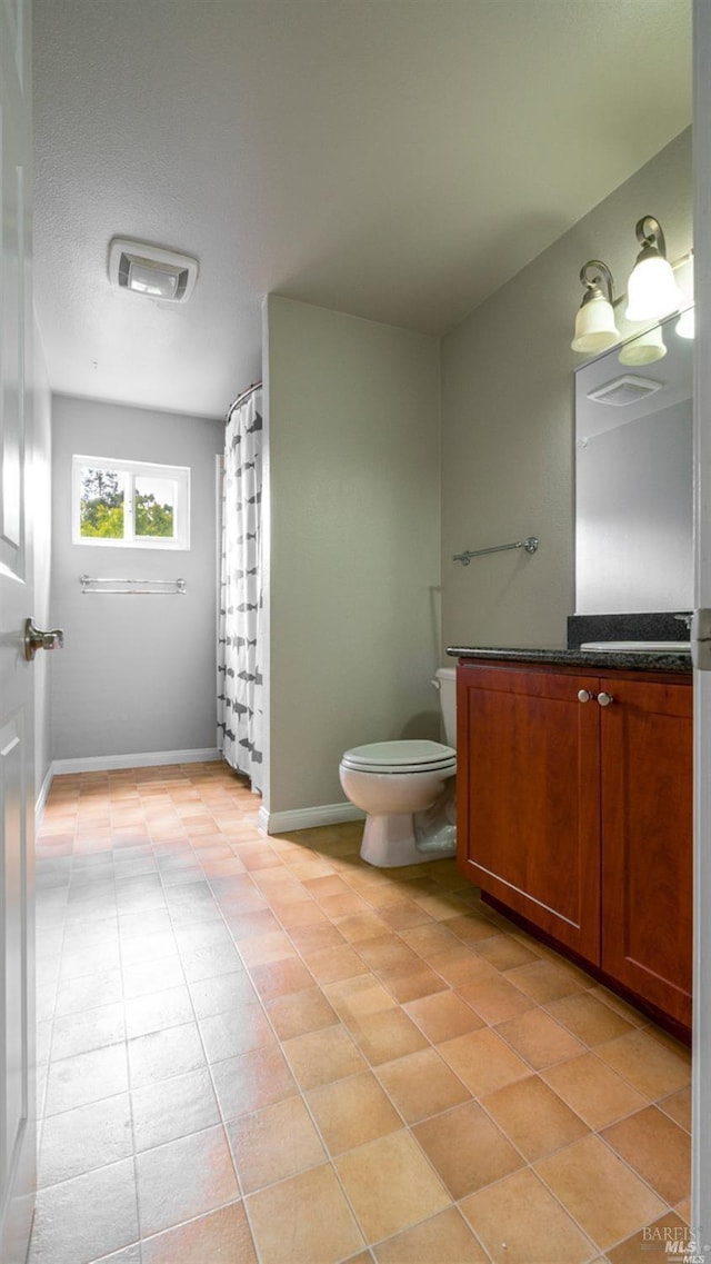 bathroom featuring toilet, vanity, and baseboards