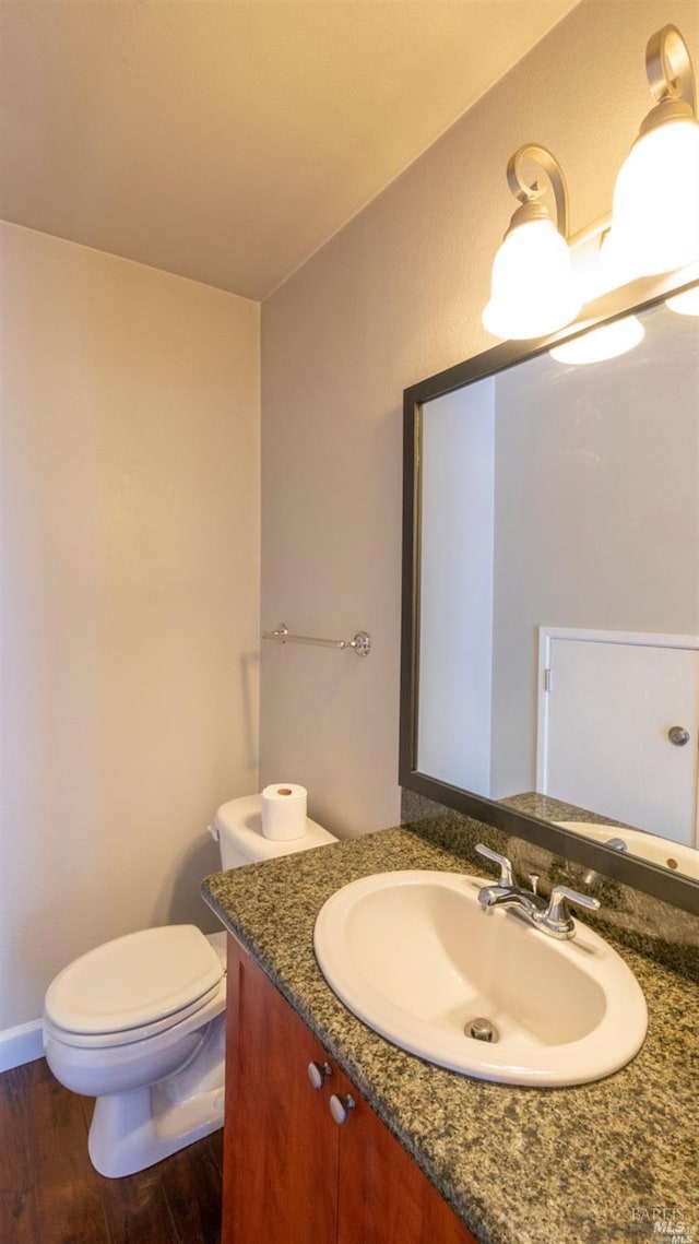 half bath with vanity, toilet, and wood finished floors