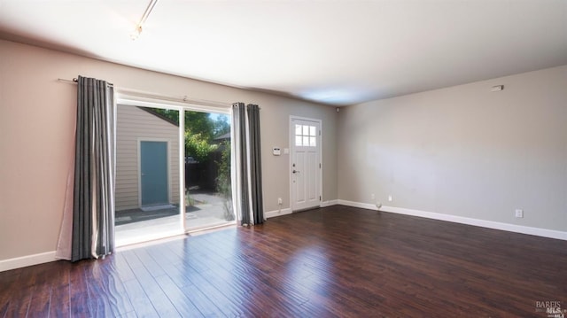 spare room with baseboards and wood finished floors