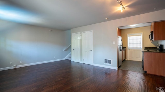 interior space featuring rail lighting, visible vents, stairway, dark wood-style flooring, and baseboards