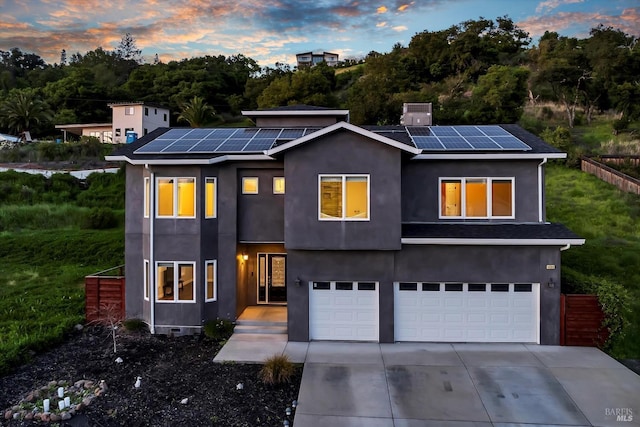 modern home featuring roof mounted solar panels, driveway, a garage, and stucco siding