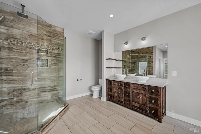 bathroom with a shower stall, a sink, double vanity, baseboards, and toilet