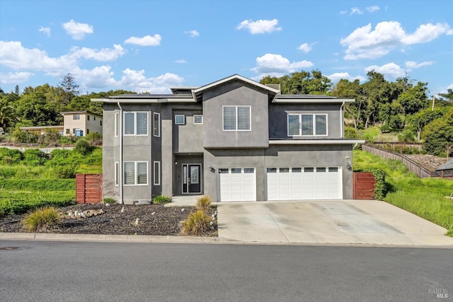 view of front of property featuring roof mounted solar panels, concrete driveway, an attached garage, and stucco siding