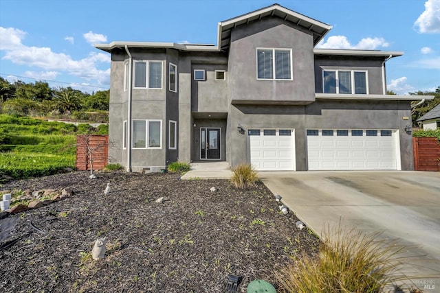 view of front facade featuring an attached garage, concrete driveway, and stucco siding