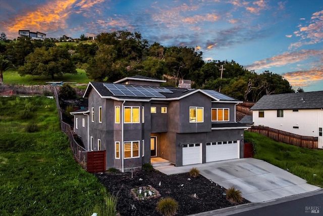 view of front of property featuring stucco siding, fence, a garage, solar panels, and concrete driveway