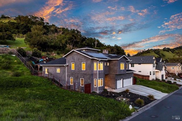 exterior space featuring a garage, concrete driveway, solar panels, stucco siding, and fence