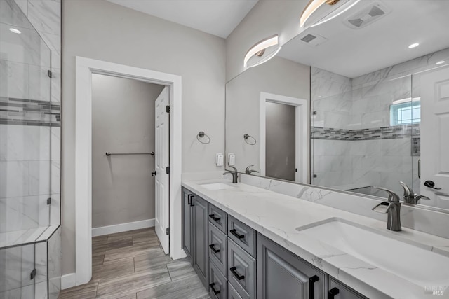 bathroom with visible vents, tiled shower, and a sink