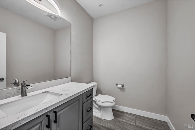 half bath featuring vanity, toilet, and baseboards