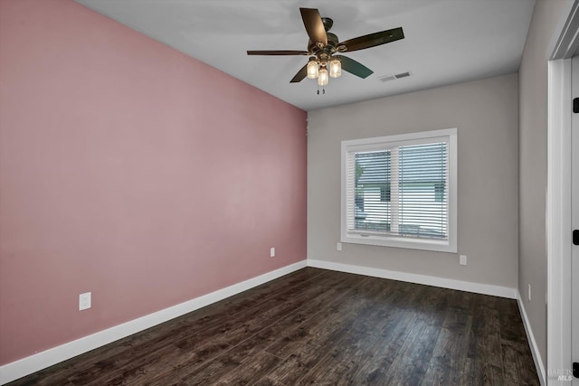 unfurnished room with dark wood-type flooring, visible vents, a ceiling fan, and baseboards