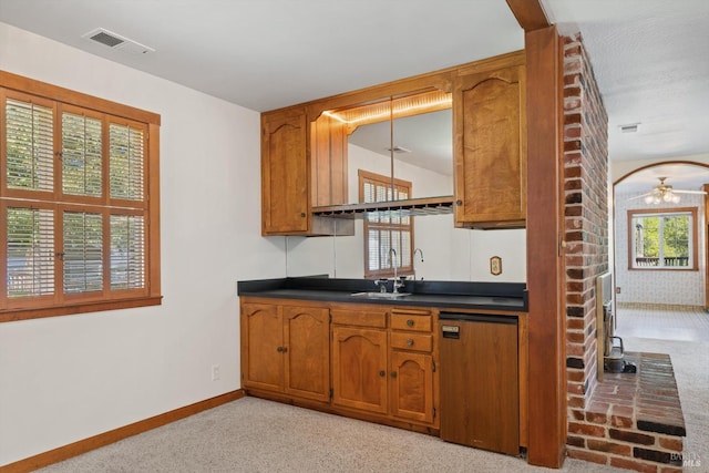 kitchen with light carpet, visible vents, a sink, and brown cabinets