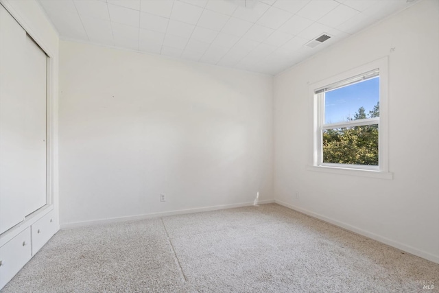 carpeted spare room featuring baseboards and visible vents