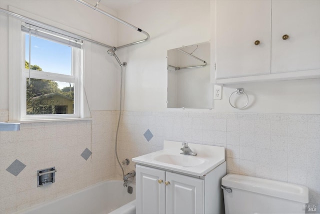 bathroom with a wainscoted wall, shower / bath combination, vanity, toilet, and tile walls
