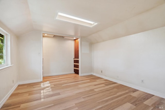 bonus room with light wood-style flooring, lofted ceiling, and baseboards