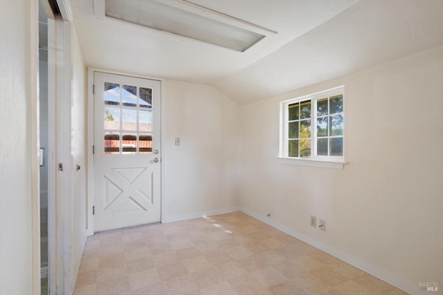 unfurnished room with plenty of natural light, lofted ceiling, baseboards, and light floors