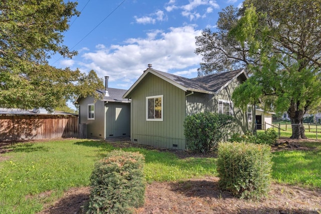 rear view of house featuring a lawn, crawl space, fence, and roof with shingles