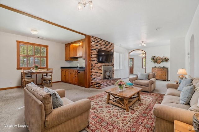 living area featuring visible vents, arched walkways, baseboards, light colored carpet, and a notable chandelier