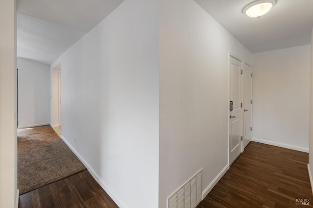 corridor featuring wood finished floors, baseboards, and visible vents