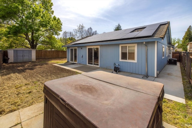back of property with solar panels, a patio area, a fenced backyard, an outdoor structure, and a storage unit