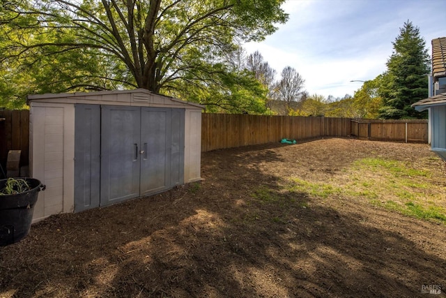 view of yard featuring a shed, a fenced backyard, and an outbuilding