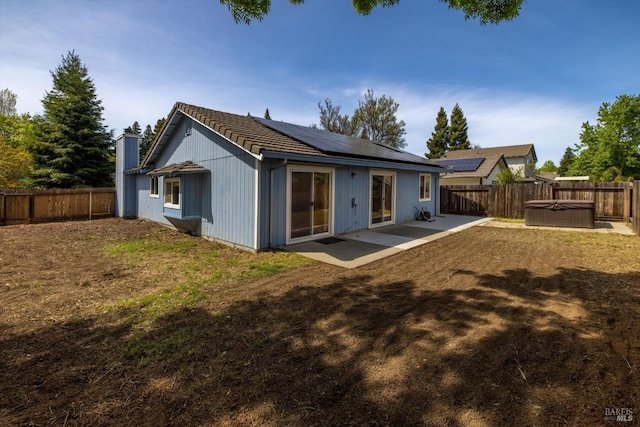 back of house with a patio, a tiled roof, a fenced backyard, and roof mounted solar panels