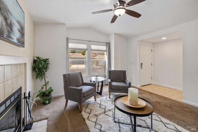 living area with baseboards, a tiled fireplace, lofted ceiling, and carpet