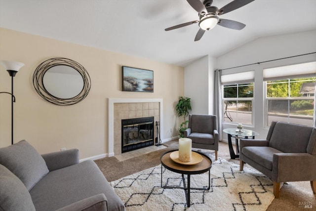 living room with carpet, a ceiling fan, a tiled fireplace, lofted ceiling, and baseboards