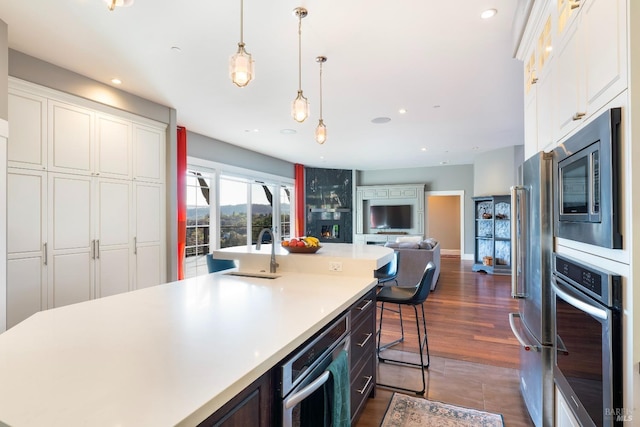 kitchen with open floor plan, light countertops, white cabinets, a sink, and stainless steel appliances