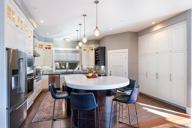 kitchen featuring decorative backsplash, a breakfast bar area, a center island, a sink, and appliances with stainless steel finishes